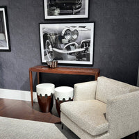 Console table beneath black-and-white photography and chair.