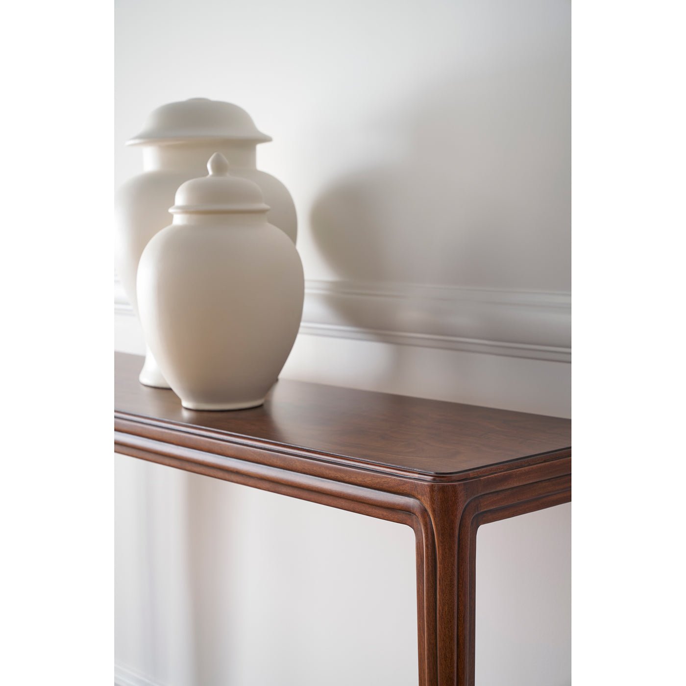 Console table with vases, detail of tabletop and wall.