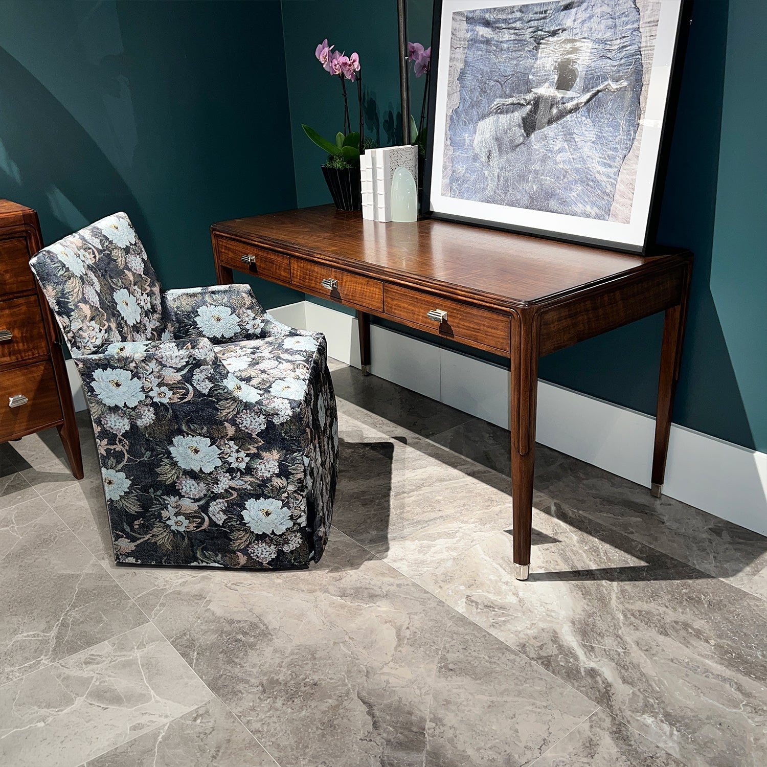 Decorated walnut desk in room with floral chair.