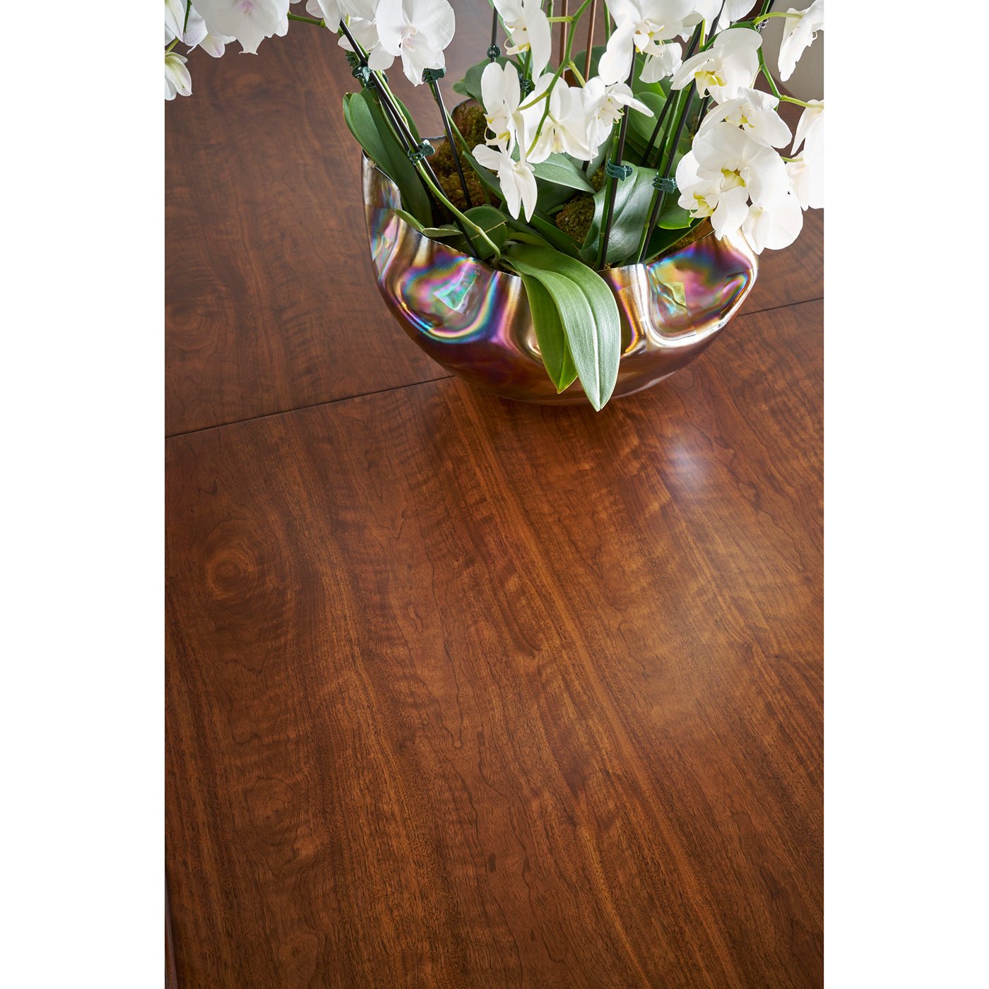 Polished walnut dining table surface with floral centerpiece.