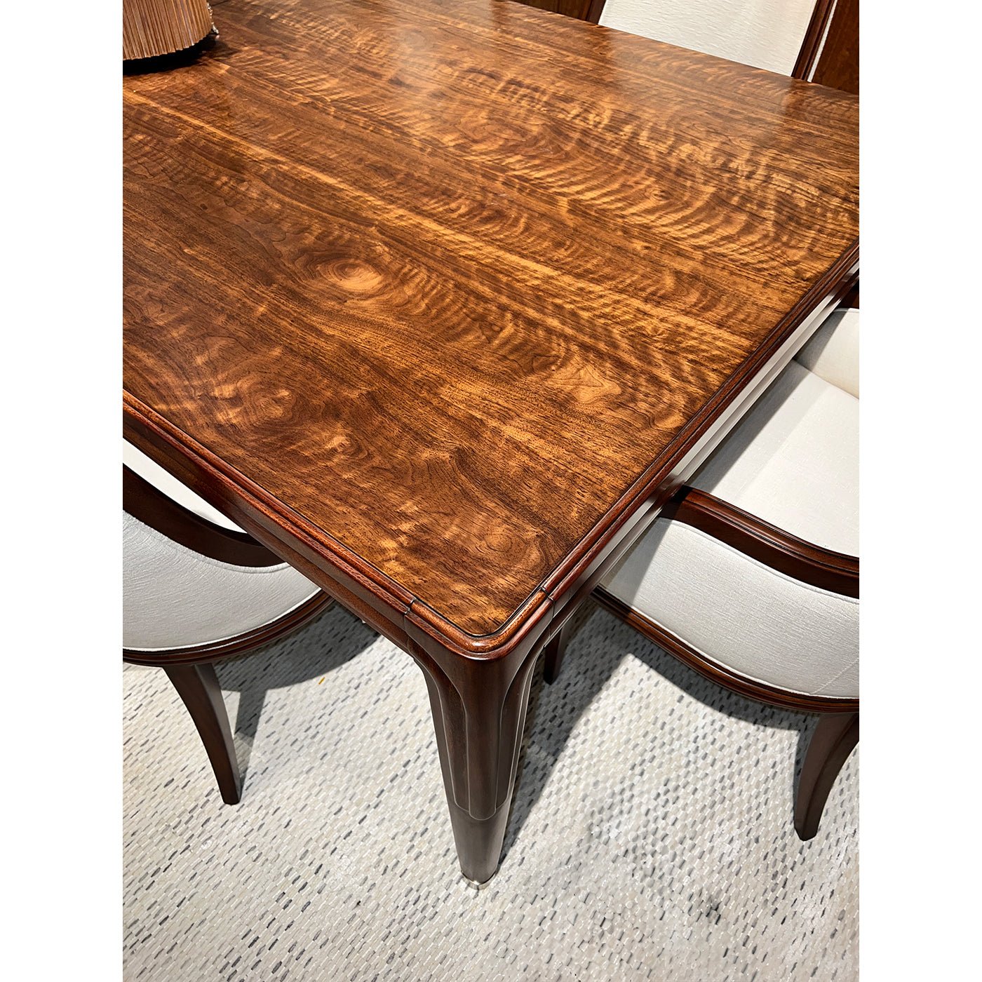 Close-up of walnut dining table corner and seat.