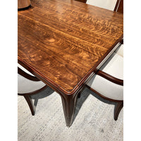 Close-up of walnut dining table corner and seat.