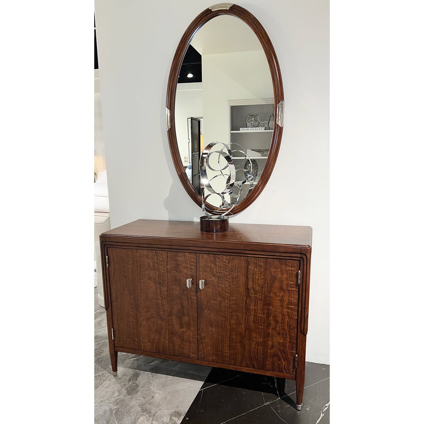 Oval mirror on wooden cabinet, modern decor displayed.