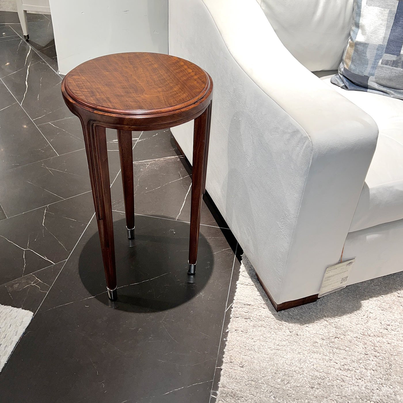 Walnut art deco accent table beside white sofa.