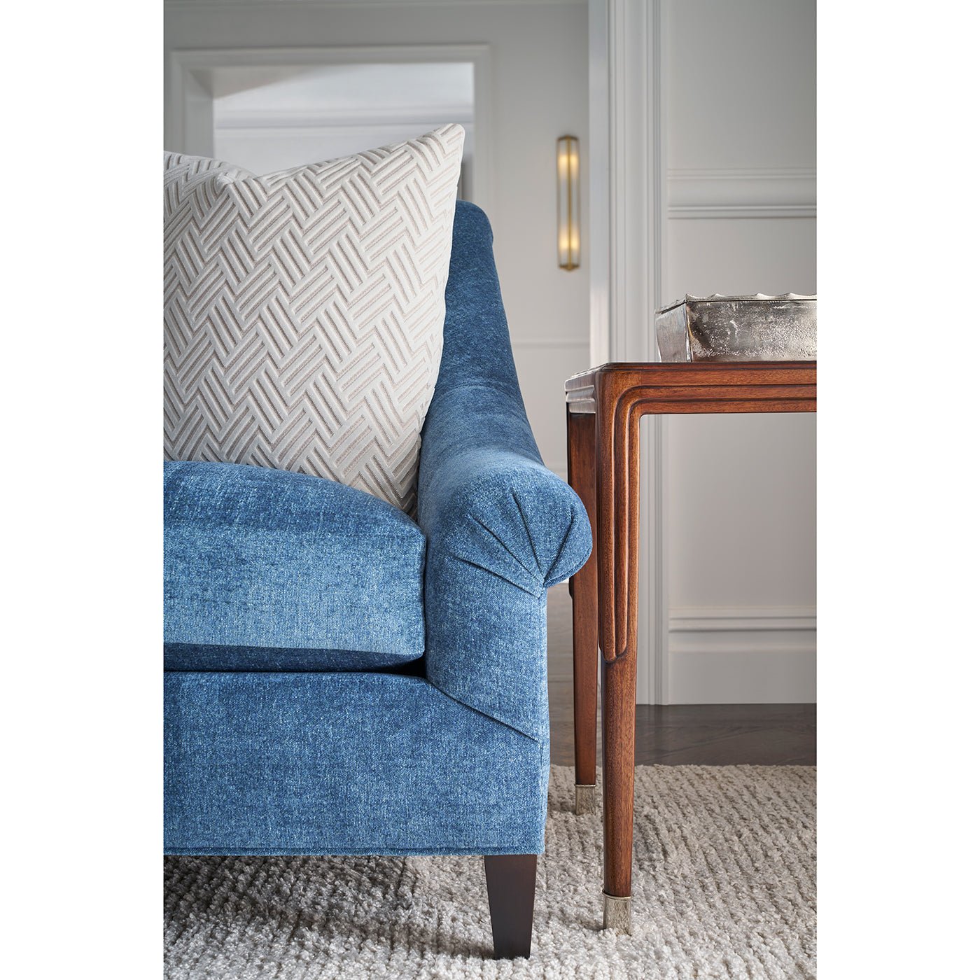 Side table next to blue sofa with pillow.