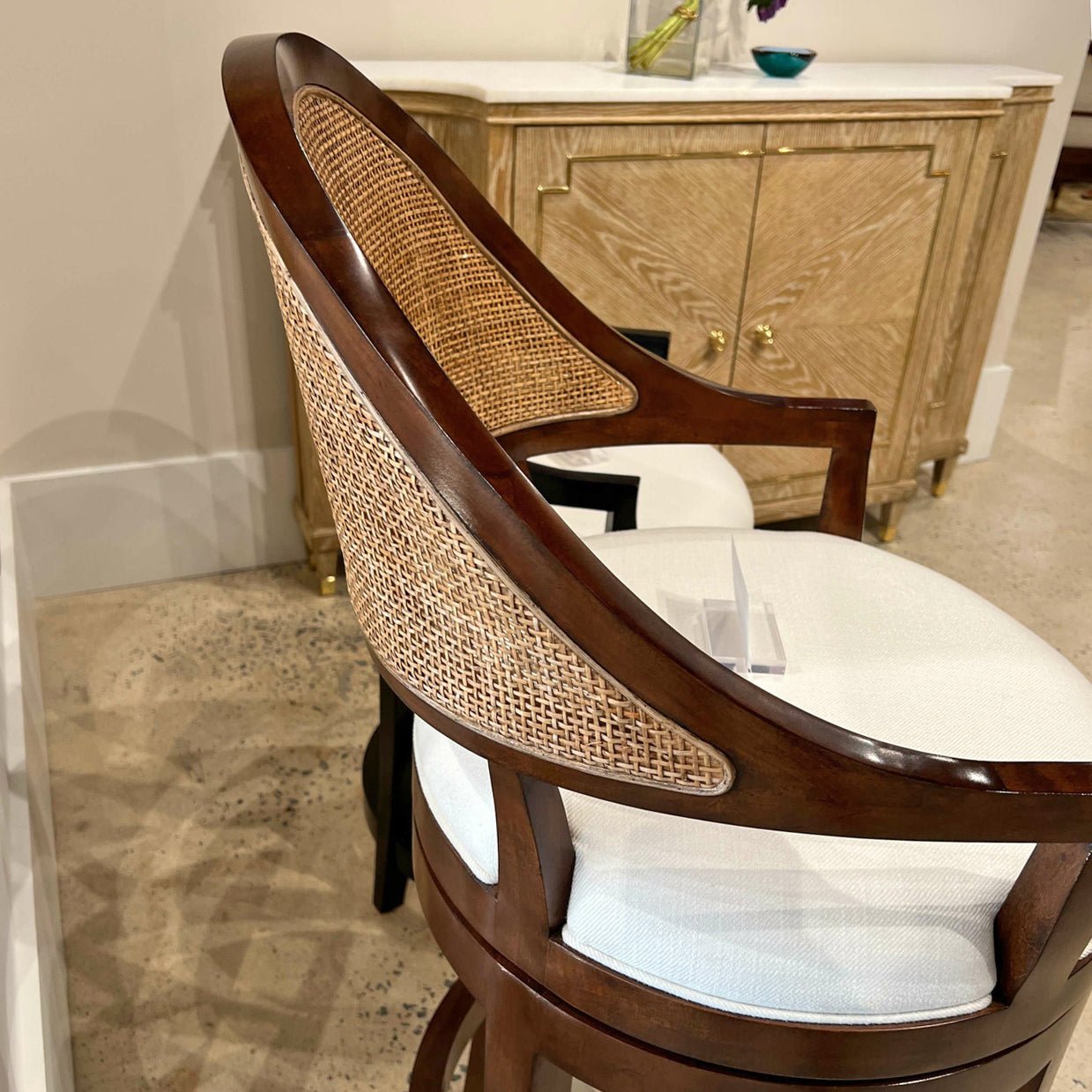 Close-up of walnut swivel bar stool, wicker backrest detail.