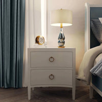 Nightstand with lamp beside bed in cozy interior.