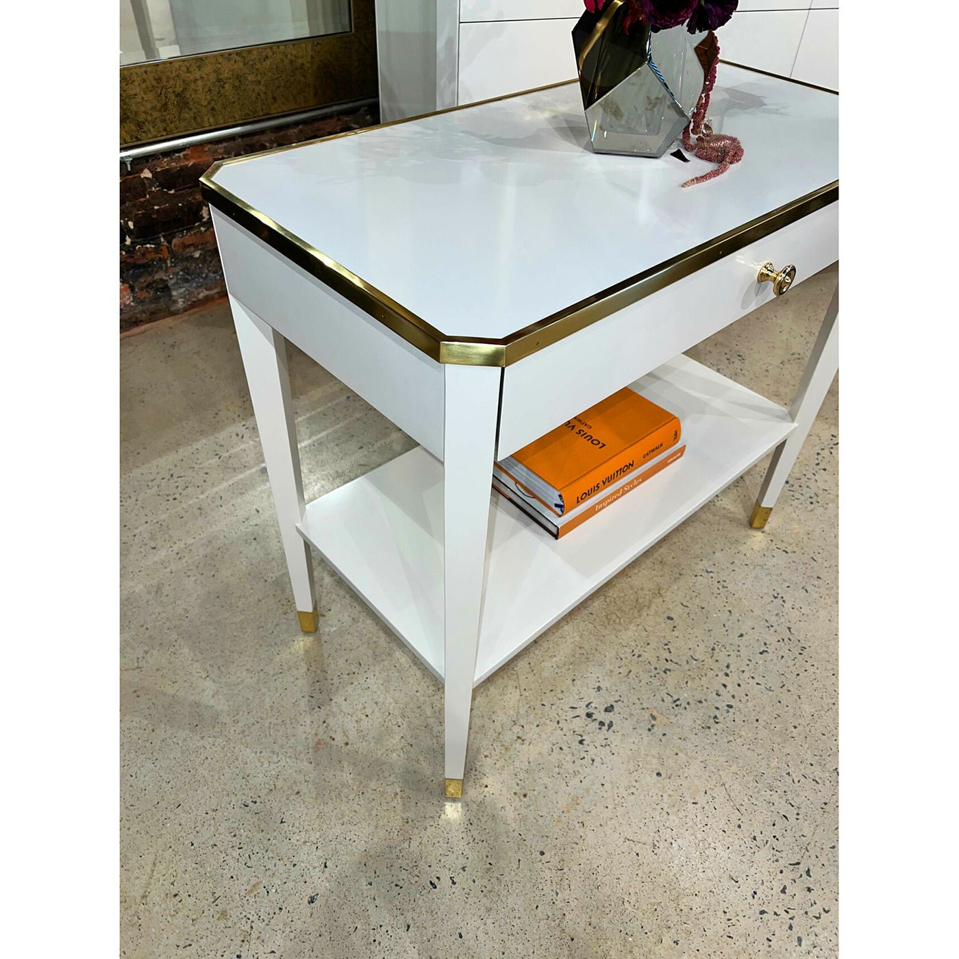Angled view of White Mid Century bedside table with books.