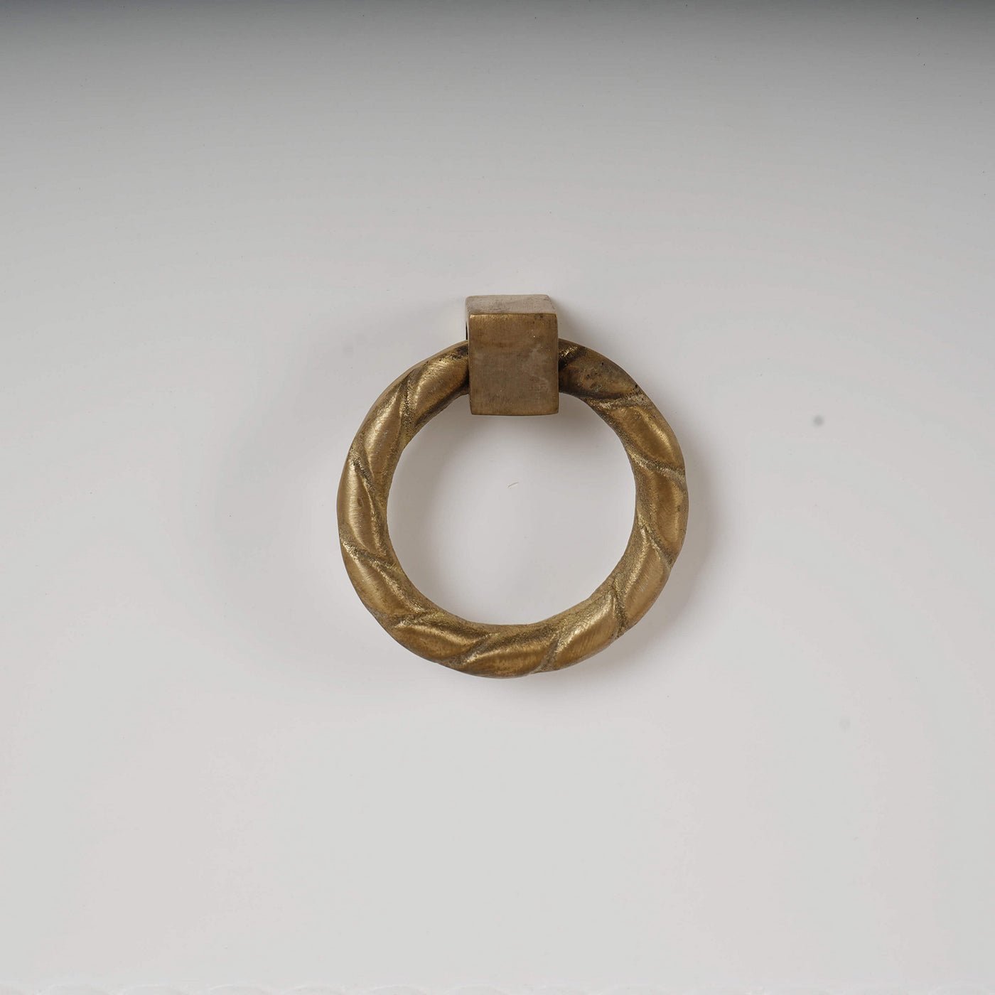 Gold ring handle detail on white dresser.