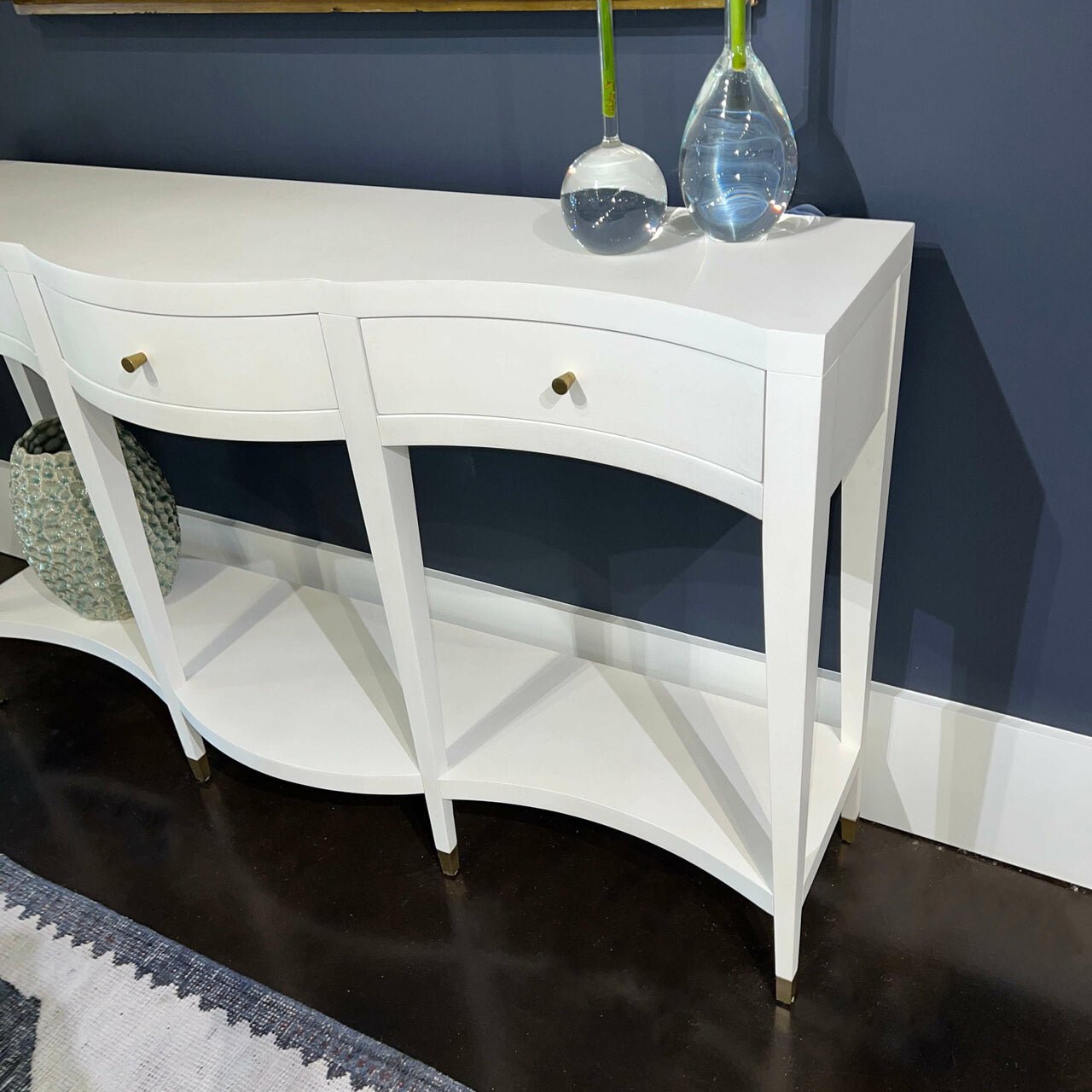 White console table with vases, dark wall background.