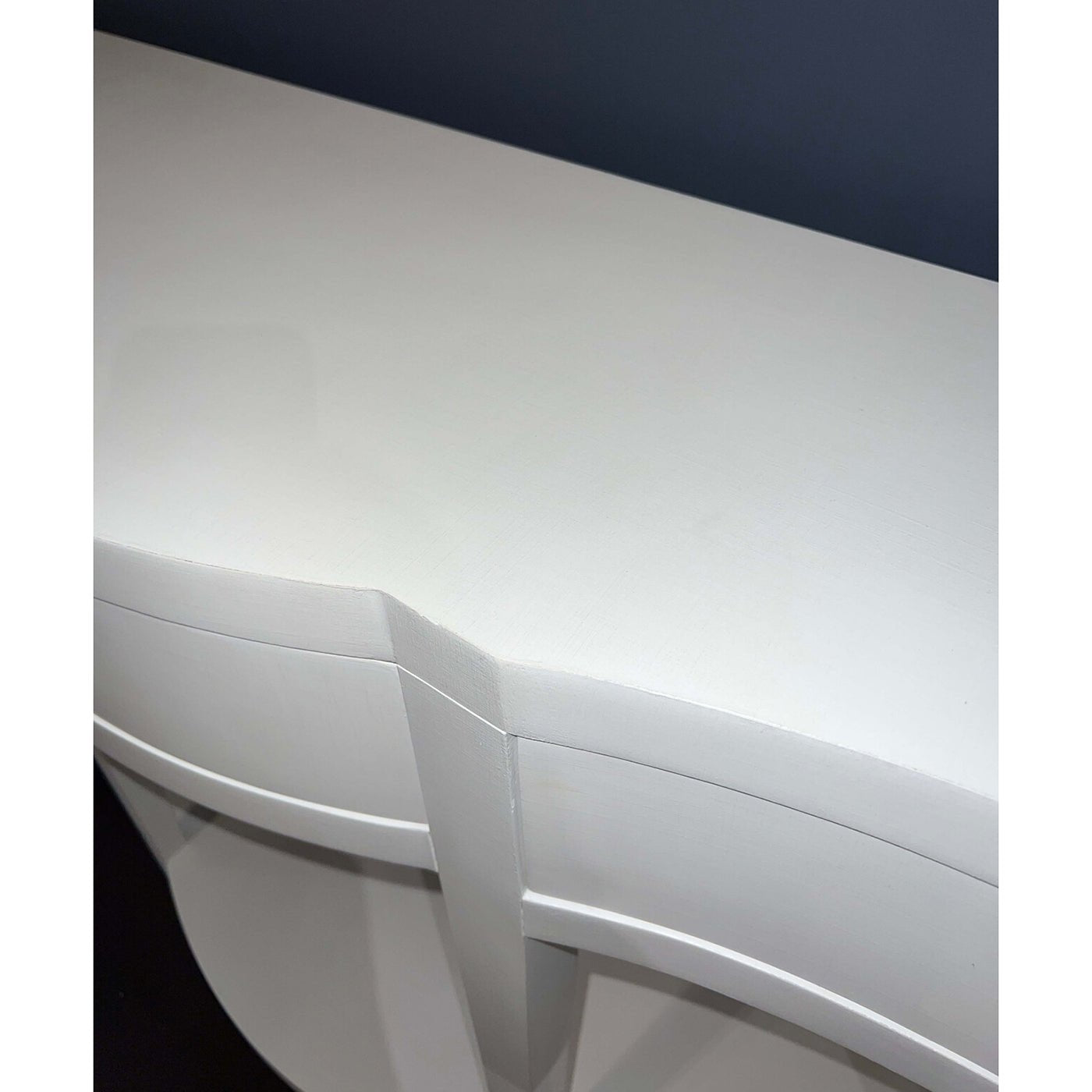 Close-up of white curved console table surface detail.