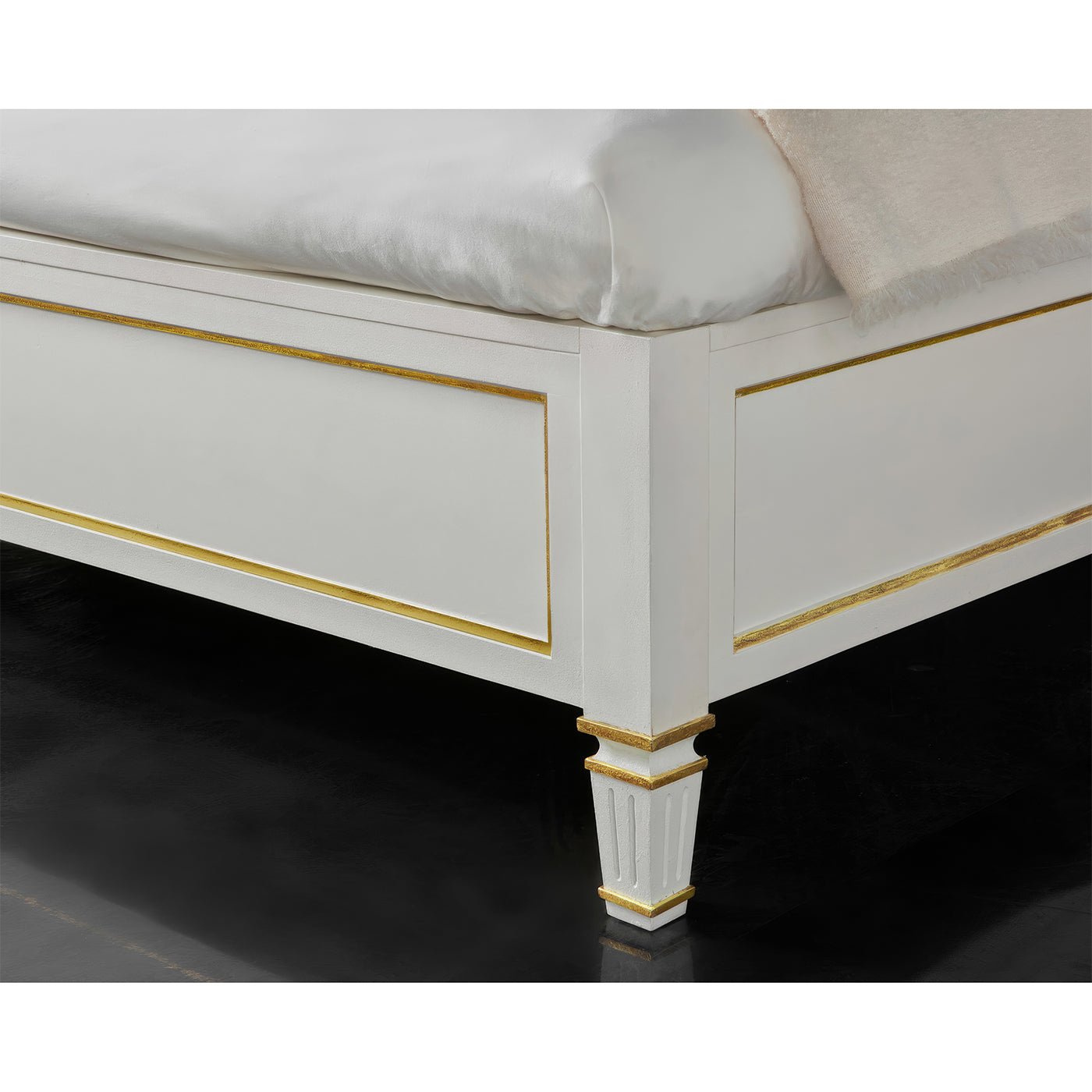 White king platform bed footboard with gold accents, close-up.