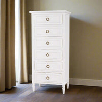 Lingerie chest in room with curtains and wood floor.
