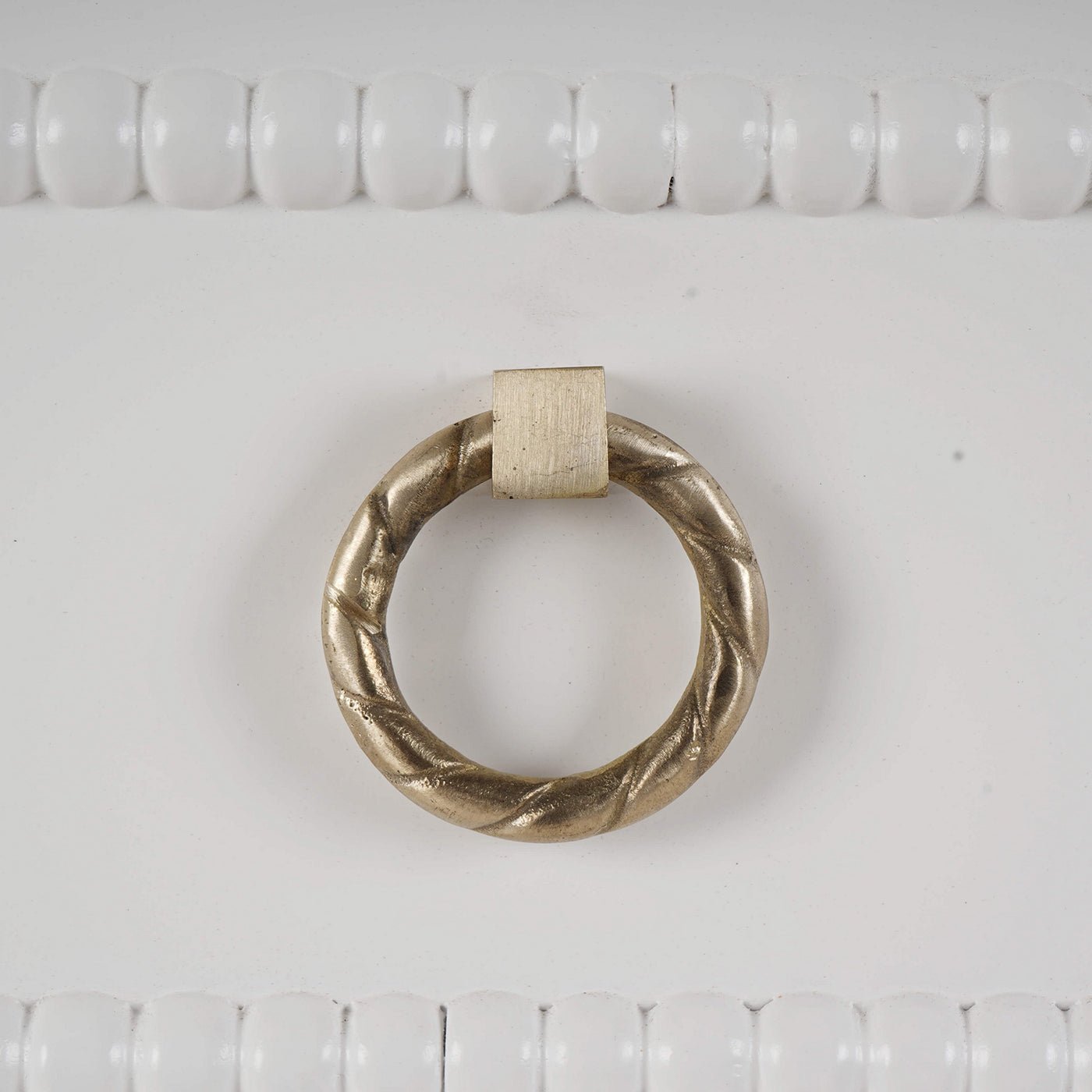 Close-up of ornate ring handle on white chest.