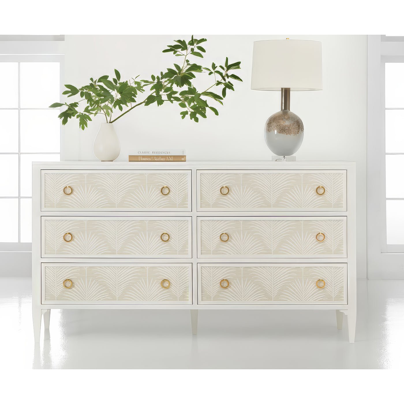 White dresser styled with plant and lamp.