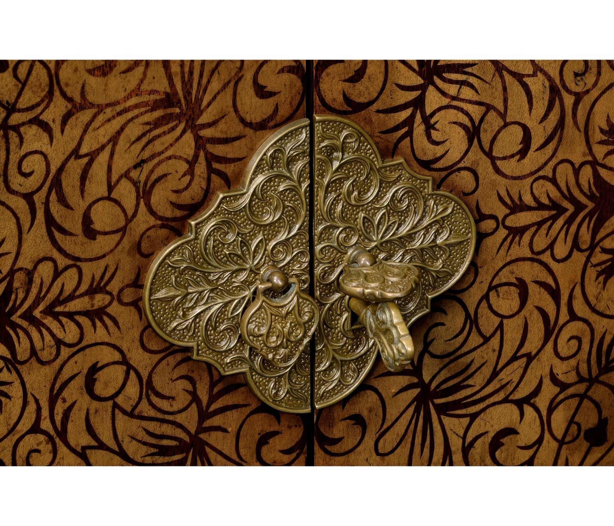 Close-up of cabinet latch, ornate floral metal design.
