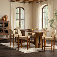 Natural woven abaca counter stools gathered around a tall wood table in a room with arched windows