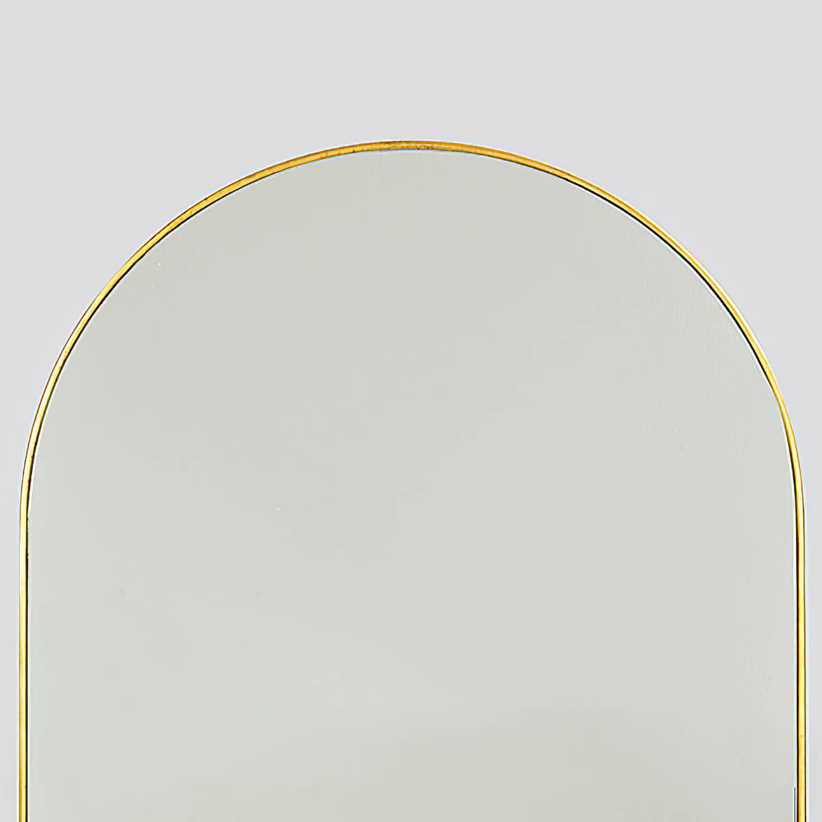 Close-up gold-framed arch mirror top detail.