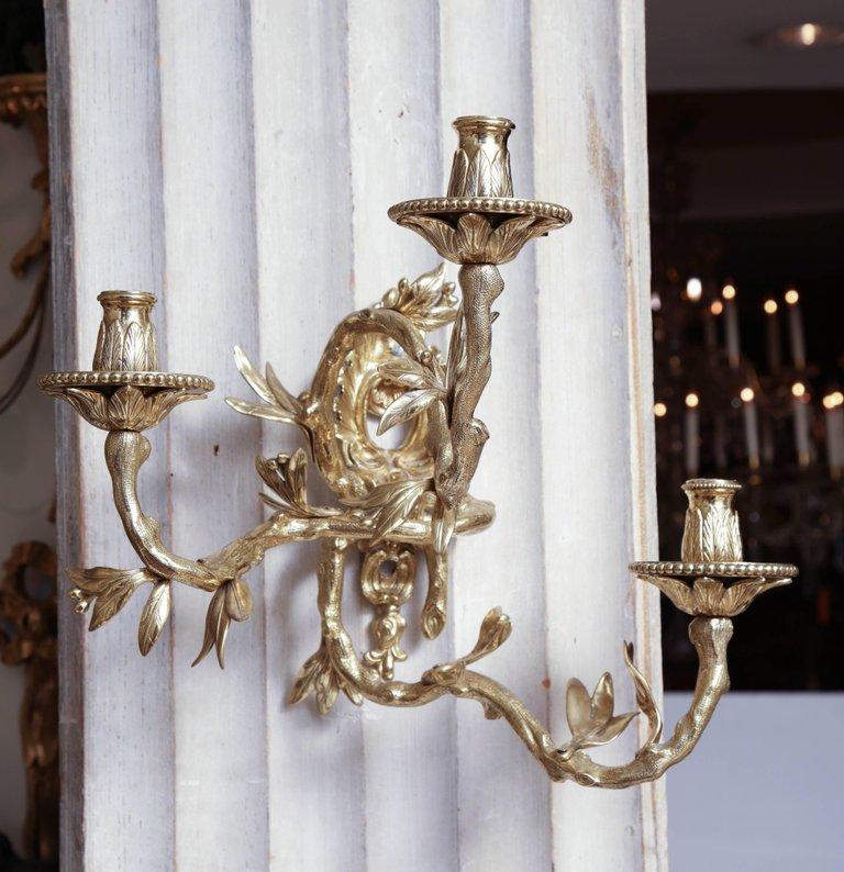 Detailed view of bronze sconce with three candle holders.