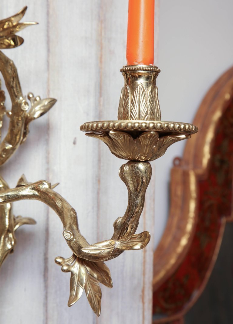 Bronze sconce with orange candle in decorative holder.