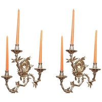 Pair of bronze sconces with orange candles lit.