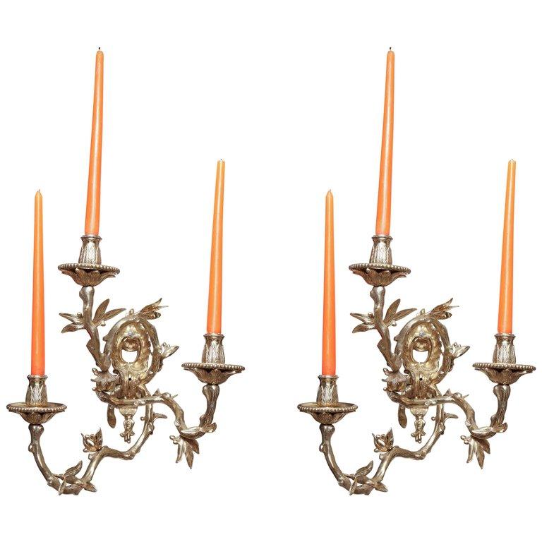 Pair of bronze sconces with orange candles lit.