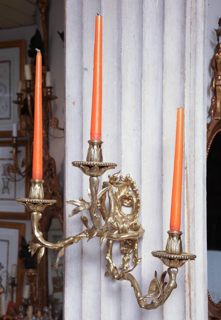 Pair of bronze sconces with orange taper candles.