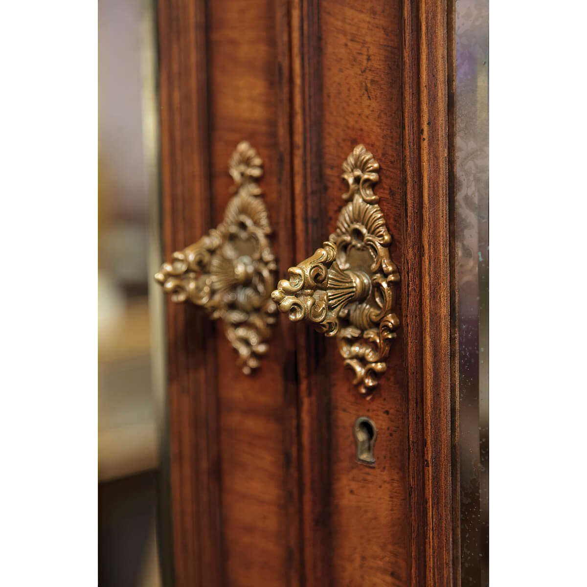 Antique-style brass handle detail on walnut bookcase.